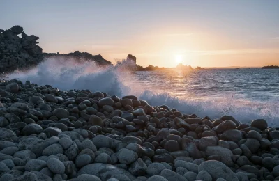 Waves crashing against a rocky shoreline at sunset